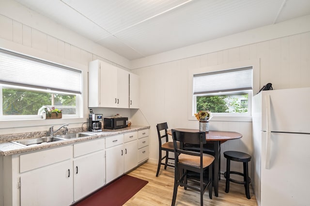 14 15th St, Cloquet, MN 55720 - kitchen with freestanding refrigerator, black microwave, light wood-type flooring, white cabinetry, and light countertops