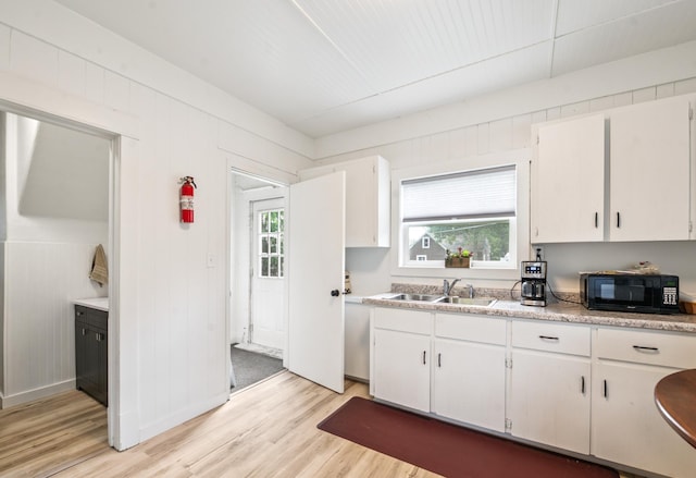 14 15th St, Cloquet, MN 55720 - kitchen featuring black microwave, light wood-type flooring, light countertops, and white cabinetry