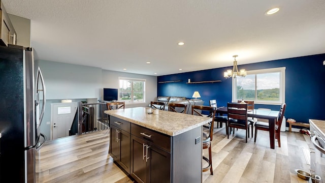 1280 Lone Stone Ct SE, Chatfield, MN 55923 - kitchen with freestanding refrigerator, a chandelier, light wood-type flooring, dark brown cabinets, and a breakfast bar area