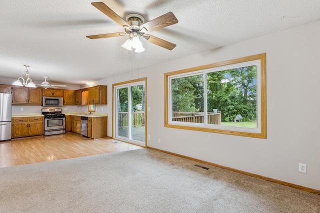 11716 54th St NE, Albertville, MN 55301 - kitchen with stainless steel appliances, light colored carpet, light countertops, brown cabinets, and a chandelier