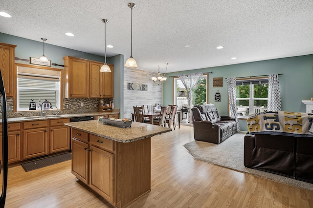 11259 69th St NE, Albertville, MN 55301 - kitchen with a textured ceiling, a kitchen island, light wood finished floors, brown cabinets, and a chandelier