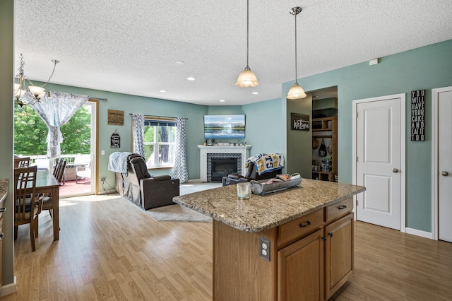 11259 69th St NE, Albertville, MN 55301 - kitchen featuring a textured ceiling, light wood-type flooring, a glass covered fireplace, pendant lighting, and a chandelier