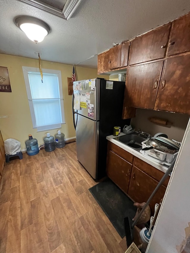 102 4th St S, Grove City, MN 56243 - kitchen featuring freestanding refrigerator, light wood finished floors, a textured ceiling, and light countertops