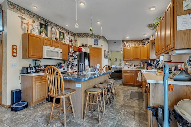 43054 105th Ave, Brockway Twp, MN 56367 - kitchen featuring a kitchen island, fridge with ice dispenser, white microwave, a breakfast bar, and brown cabinets