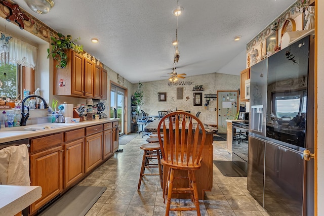 43054 105th Ave, Brockway Twp, MN 56367 - kitchen with stainless steel refrigerator with ice dispenser, a textured ceiling, lofted ceiling, brown cabinetry, and a ceiling fan