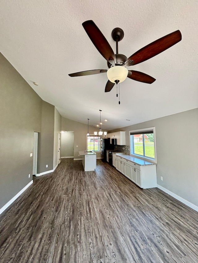 2032 Reuss Pkwy, Saint Croix Falls, WI 54024 - unfurnished living room featuring a ceiling fan, dark wood-style floors, plenty of natural light, vaulted ceiling, and a textured ceiling