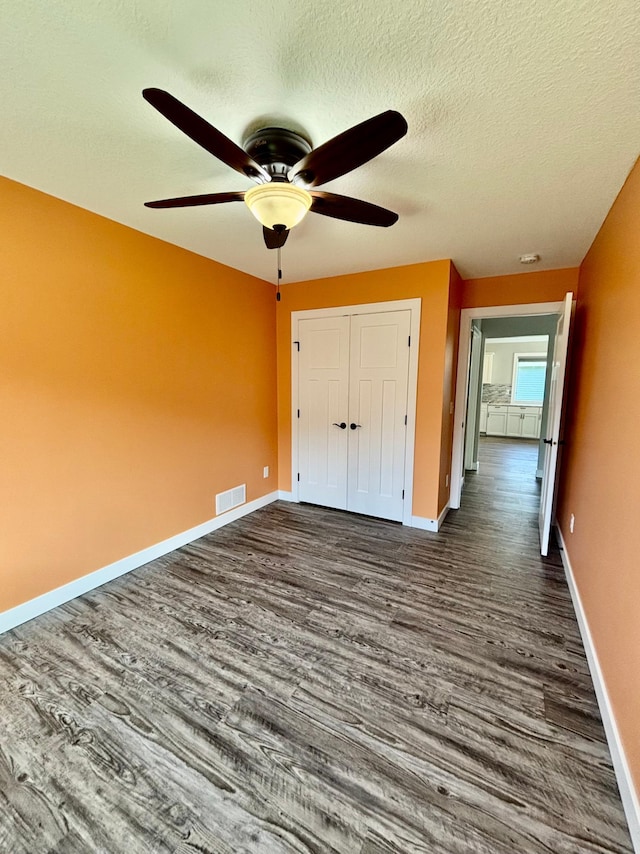 2032 Reuss Pkwy, Saint Croix Falls, WI 54024 - unfurnished bedroom with dark wood-type flooring, a closet, a textured ceiling, and a ceiling fan