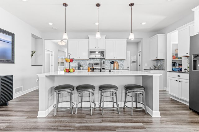 19621 115th Ave N, Rogers, MN 55311 - kitchen with backsplash, white cabinets, wood finished floors, appliances with stainless steel finishes, and recessed lighting