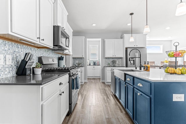 19621 115th Ave N, Rogers, MN 55311 - kitchen featuring blue cabinets, stainless steel appliances, white cabinetry, light wood finished floors, and decorative backsplash