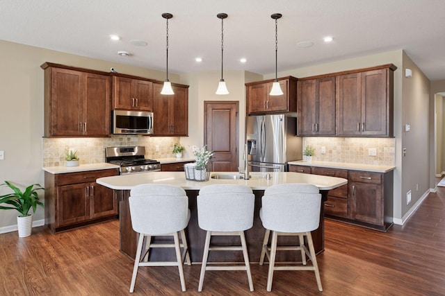7461 Fir Ln N, Corcoran, MN 55340 - kitchen featuring appliances with stainless steel finishes, a center island with sink, decorative backsplash, light countertops, and a kitchen bar