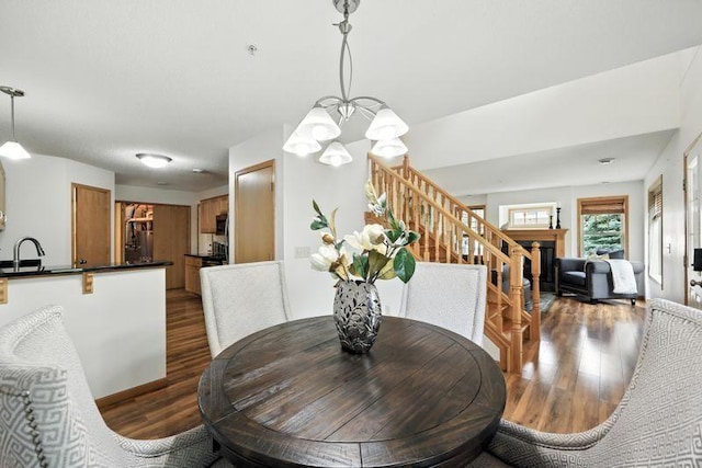 5460 100th Ln N, Brooklyn Park, MN 55443 - dining room featuring stairs, dark wood-style flooring, a chandelier, and a fireplace