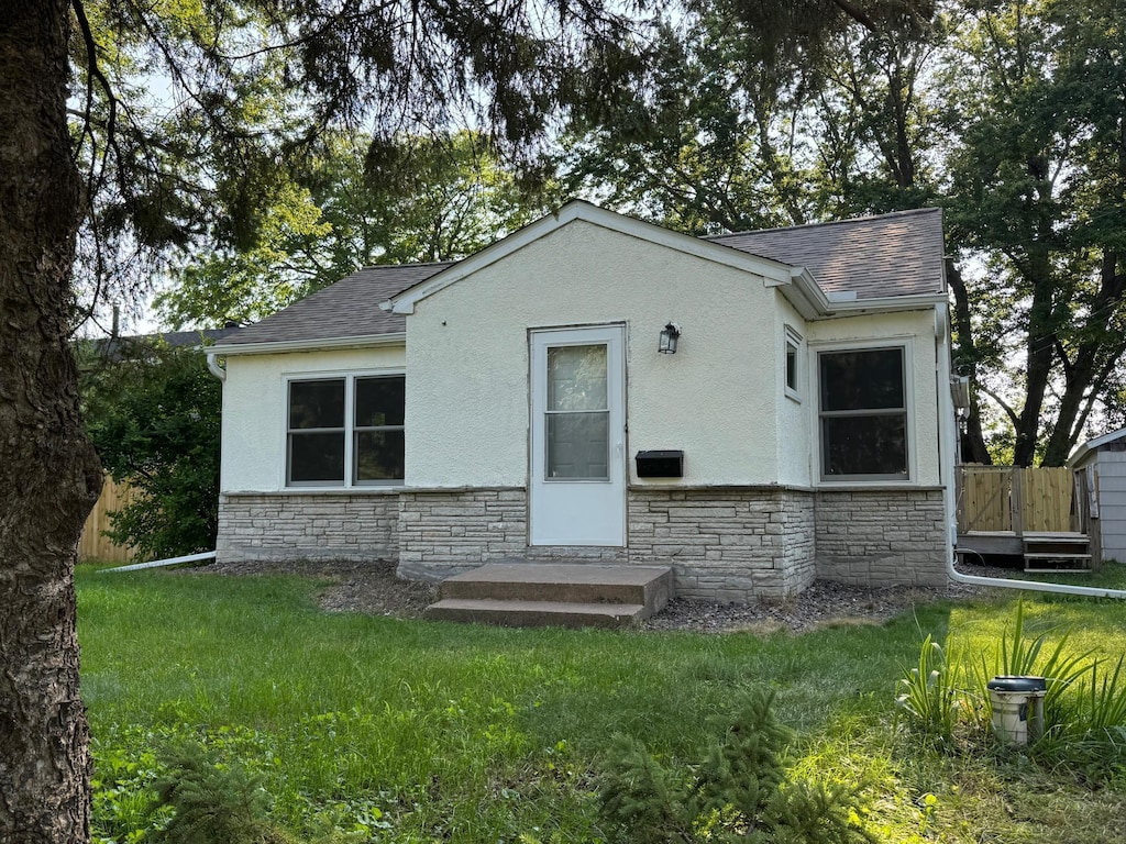 33858 Hastings St NE, Cambridge Twp, MN 55008 - back of property featuring stone siding, a shingled roof, and a lawn