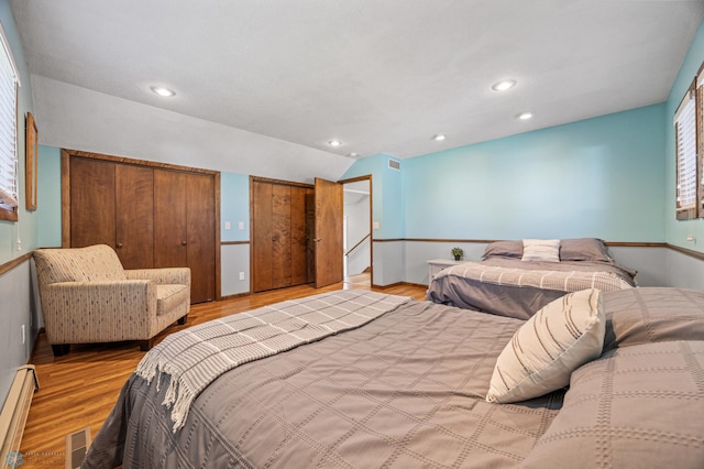 44042 Outlet Beach Rd, Lida Twp, MN 56572 - bedroom featuring wood finished floors, a baseboard heating unit, vaulted ceiling, recessed lighting, and multiple closets