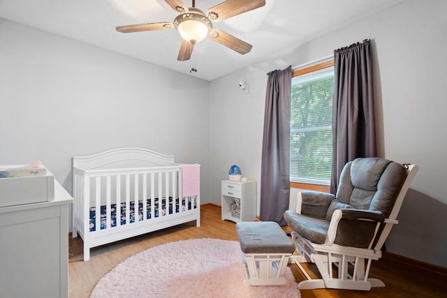 10919 Eagle St NW, Coon Rapids, MN 55433 - bedroom with a crib, wood finished floors, and a ceiling fan