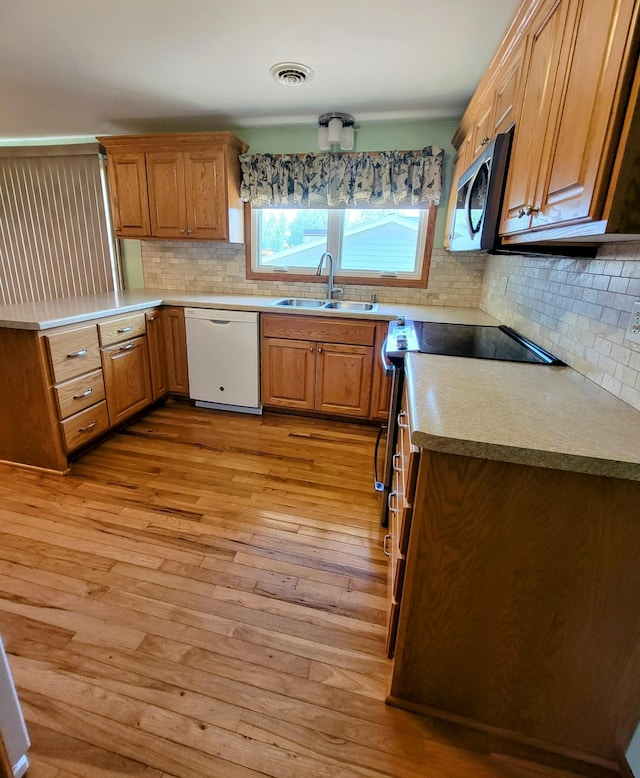 619 3rd St NW, Forest Lake, MN 55025 - kitchen with white dishwasher, stainless steel microwave, decorative backsplash, light wood-type flooring, and a peninsula