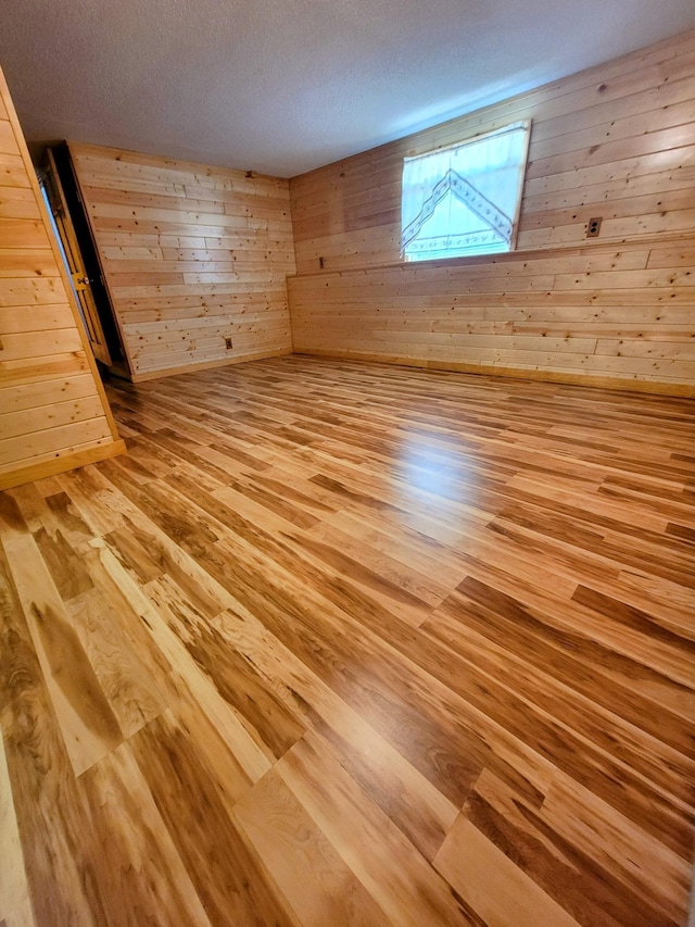 619 3rd St NW, Forest Lake, MN 55025 - spare room with light wood-style flooring, wooden walls, and a textured ceiling