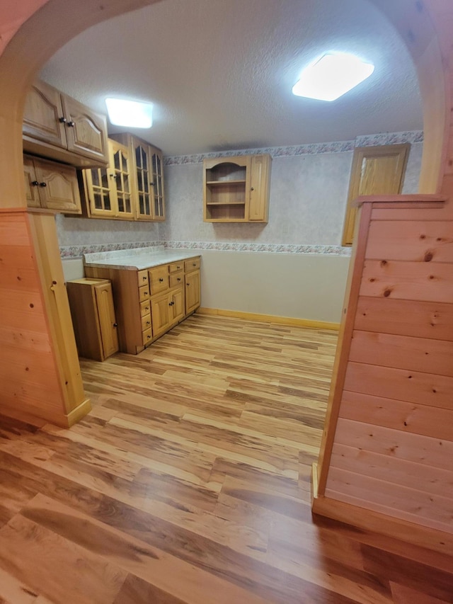 619 3rd St NW, Forest Lake, MN 55025 - kitchen featuring light wood finished floors, glass insert cabinets, arched walkways, light countertops, and open shelves