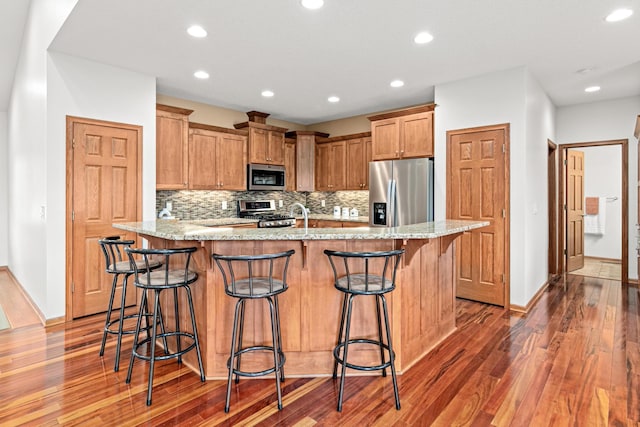 12605 314th St, Lindstrom, MN 55045 - kitchen with appliances with stainless steel finishes, wood finished floors, recessed lighting, decorative backsplash, and a breakfast bar