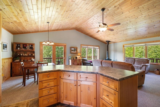 1063 Fernberg Rd, Fall Lake Twp, MN 55731 - kitchen featuring a wood stove, carpet flooring, wainscoting, ceiling fan, and plenty of natural light