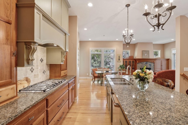 17244 Valley Rd, Eden Prairie, MN 55347 - kitchen featuring stainless steel appliances, light wood-style flooring, a chandelier, light stone counters, and decorative backsplash