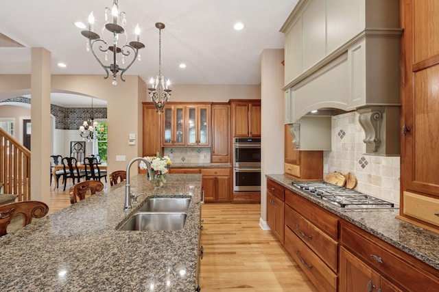 17244 Valley Rd, Eden Prairie, MN 55347 - kitchen with stainless steel appliances, a chandelier, arched walkways, light wood-style floors, and brown cabinets