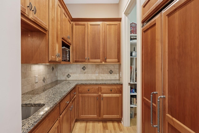 17244 Valley Rd, Eden Prairie, MN 55347 - kitchen featuring backsplash, brown cabinets, light stone counters, and light wood-type flooring