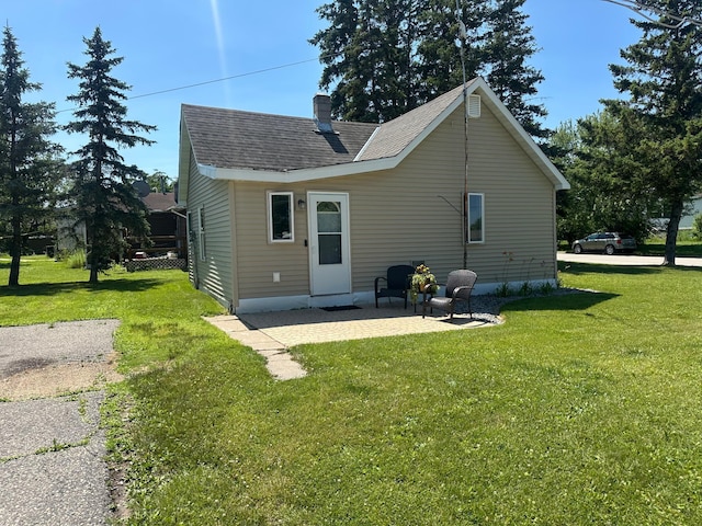 502 1st Ave SW, Baudette, MN 56623 - back of house with a chimney, a lawn, a shingled roof, and a patio