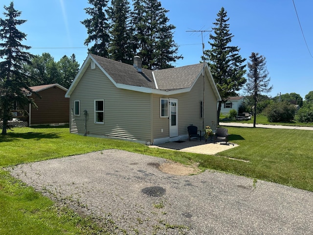 502 1st Ave SW, Baudette, MN 56623 - back of house with a yard, roof with shingles, a patio area, and a chimney