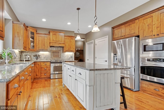 3631 Woodcrest Cir, Eagan, MN 55123 - kitchen featuring stainless steel appliances, light wood-type flooring, light stone counters, a kitchen island, and recessed lighting