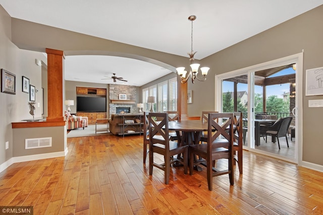 3631 Woodcrest Cir, Eagan, MN 55123 - dining space featuring a fireplace, light wood finished floors, ornate columns, ceiling fan, and arched walkways
