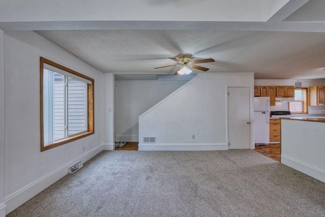 3026 5th Ave E, Hibbing, MN 55746 - unfurnished living room featuring light colored carpet, healthy amount of natural light, ceiling fan, and a textured ceiling