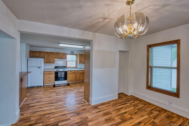 3026 5th Ave E, Hibbing, MN 55746 - kitchen featuring freestanding refrigerator, range with electric stovetop, a textured ceiling, wood finished floors, and a chandelier