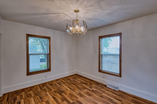 3026 5th Ave E, Hibbing, MN 55746 - empty room featuring a chandelier, wood finished floors, and a textured ceiling