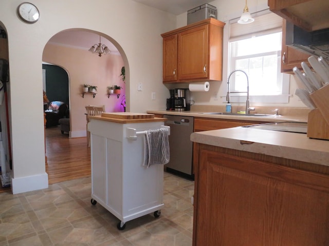 703 1st St SW, Wadena, MN 56482 - kitchen with stainless steel dishwasher, arched walkways, brown cabinetry, a kitchen island, and light countertops