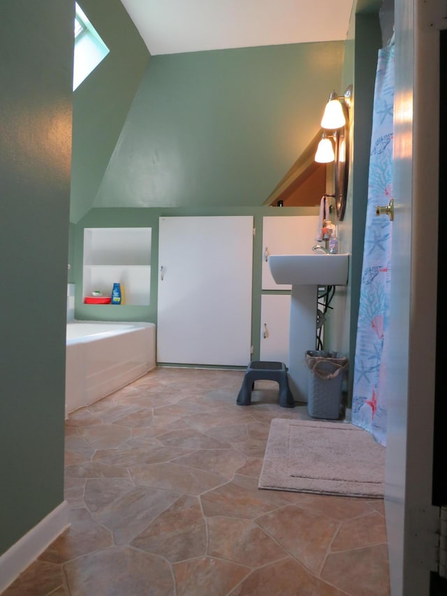 703 1st St SW, Wadena, MN 56482 - bathroom featuring lofted ceiling, stone finish flooring, a skylight, and a bath