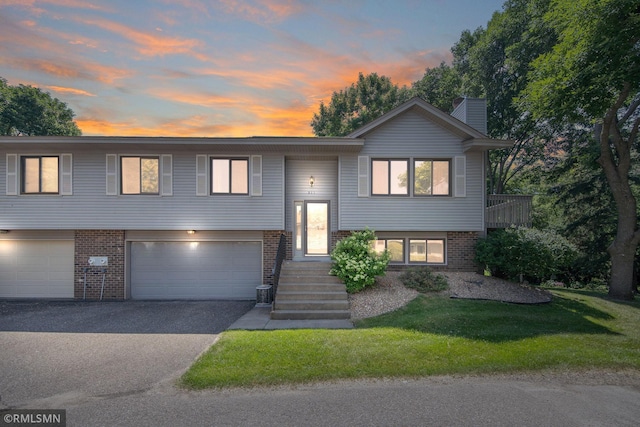 911 Lawnview Ave, Shoreview, MN 55126 - raised ranch featuring brick siding, asphalt driveway, a yard, a chimney, and a garage