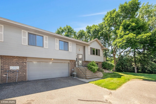 911 Lawnview Ave, Shoreview, MN 55126 - split foyer home featuring asphalt driveway, brick siding, an attached garage, and a front yard