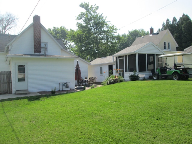 526 Red Wing Ave, Kenyon, MN 55946 - rear view of house featuring a sunroom, a chimney, a yard, and a patio