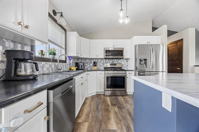 4416 10th St W, Fargo, ND 58078 - kitchen with appliances with stainless steel finishes, vaulted ceiling, dark wood finished floors, white cabinets, and backsplash
