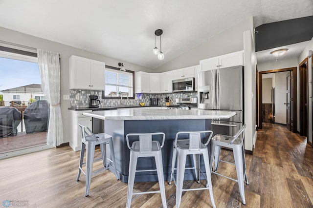 4416 10th St W, Fargo, ND 58078 - kitchen featuring appliances with stainless steel finishes, wood finished floors, a kitchen breakfast bar, tasteful backsplash, and lofted ceiling