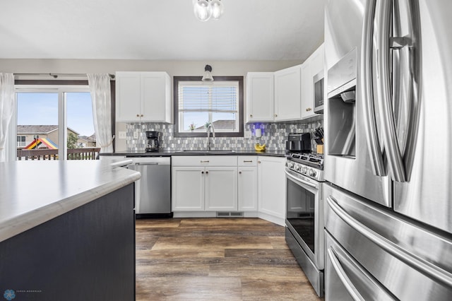 4416 10th St W, Fargo, ND 58078 - kitchen featuring stainless steel appliances, tasteful backsplash, dark wood-type flooring, and white cabinets