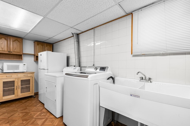 5833 Perry Ave N, Crystal, MN 55429 - laundry area featuring cabinet space, washing machine and dryer, and tile walls
