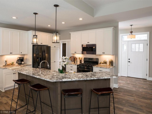 0000 Central Dr NE, Cambridge, MN 55008 - kitchen with stainless steel microwave, fridge with ice dispenser, black range with gas stovetop, a kitchen bar, and recessed lighting