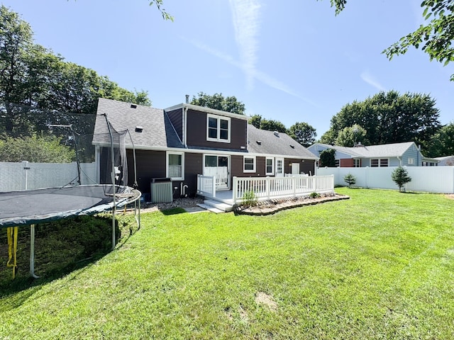 422 Galena St, Worthington, MN 56187 - rear view of house featuring a trampoline, a fenced backyard, a wooden deck, and a shingled roof