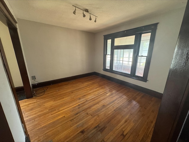 1051 Mclean Ave, Saint Paul, MN 55106 - empty room featuring rail lighting, hardwood / wood-style flooring, and a textured ceiling