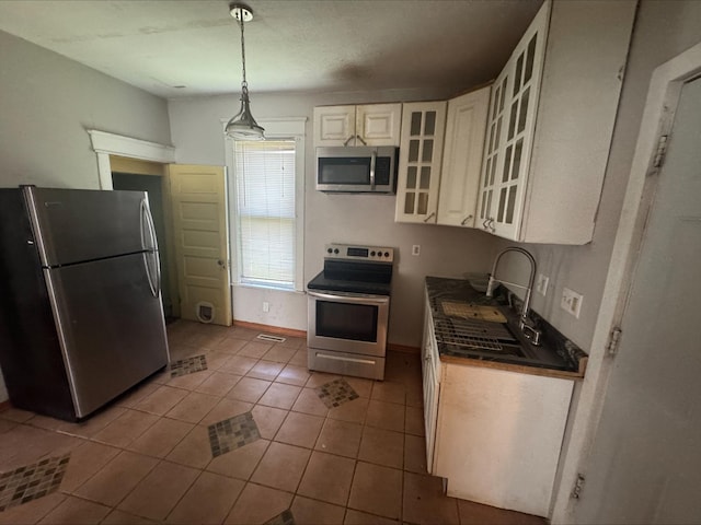 1051 Mclean Ave, Saint Paul, MN 55106 - kitchen featuring stainless steel appliances, tile patterned floors, white cabinetry, hanging light fixtures, and glass insert cabinets