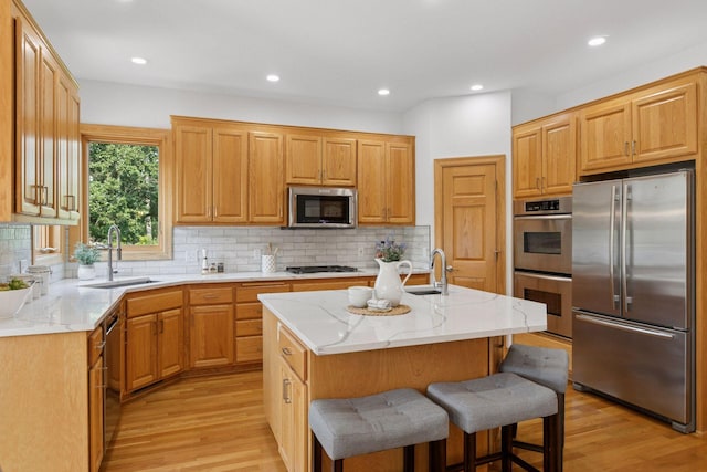 4301 Overlook Dr, Bloomington, MN 55437 - kitchen with stainless steel appliances, light wood-style floors, an island with sink, decorative backsplash, and recessed lighting