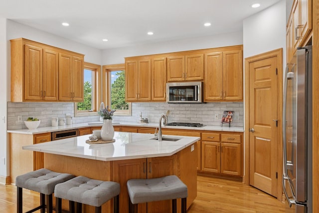 4301 Overlook Dr, Bloomington, MN 55437 - kitchen with a kitchen breakfast bar, light wood finished floors, decorative backsplash, an island with sink, and recessed lighting
