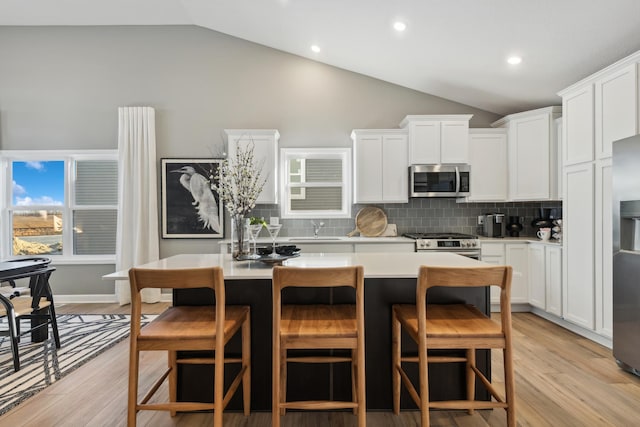930 151st Ave NW, Andover, MN 55304 - kitchen featuring appliances with stainless steel finishes, vaulted ceiling, a center island, light countertops, and decorative backsplash