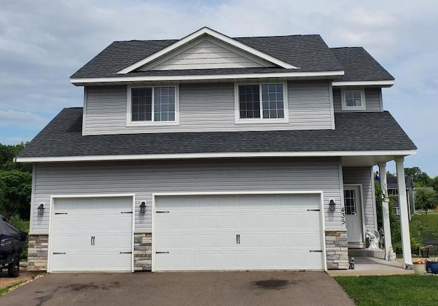 435 Alcott St E, Rush City, MN 55069 - view of front of house featuring stone siding, a garage, driveway, and roof with shingles